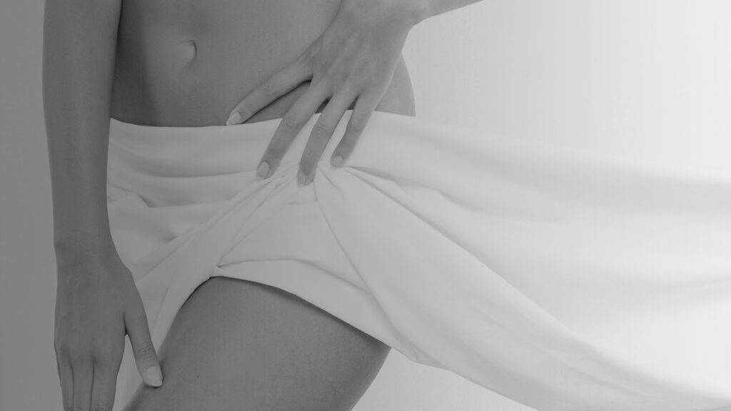 Imagen artística en blanco y negro del contorno de cadera femenina, asociada a cirugía corporal o íntima estética
