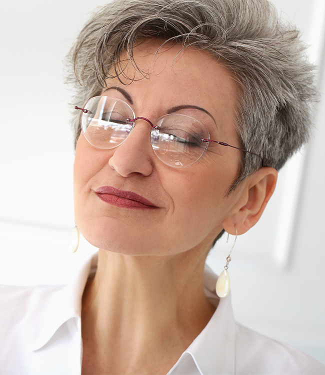 Mujer madura con gafas y expresión serena mostrando un rostro y cuello bien definidos, imagen representativa de resultados de lifting facial y cervical