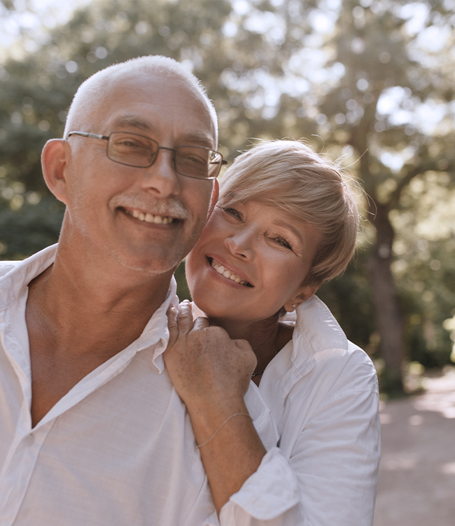 Pareja madura sonriente al aire libre con rostros naturales y descansados, imagen representativa de resultados de lipofilling facial