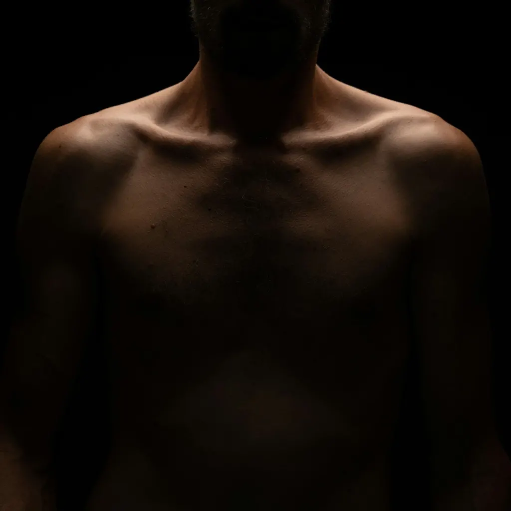 A man's shoulders and chest in shadow